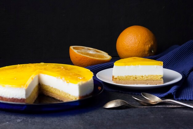 Bolo de laranja com mousse de creme e geleia de laranja em fundo escuro