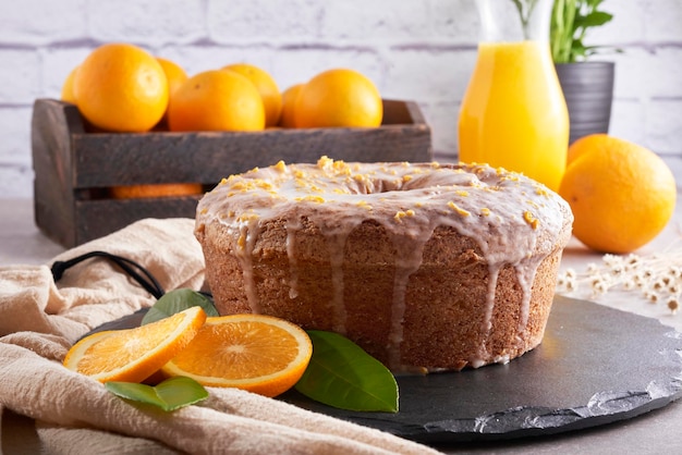 Bolo de laranja tradicional brasileiro com cobertura de raspas de laranja e limão em uma mesa de pedra