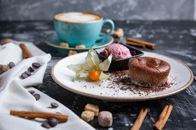 Bolo de lava de chocolate Derretido com sorvete no prato e cappuccino. Bolas de sorvete no copo. Espaço preto escuro.