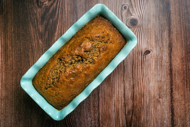 Bolo de libra em molde azul na mesa de madeira Bolo de banana caseiro