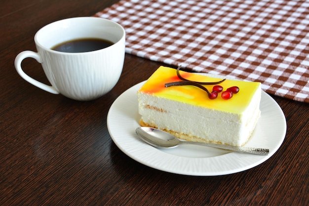 bolo de limão com creme em pires branco e café em fundo de madeira