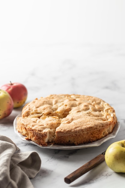 Bolo de maçã Charlotte tradicional com maçãs e faca rústica na torta de maçã de fundo marbel branco Espaço para texto