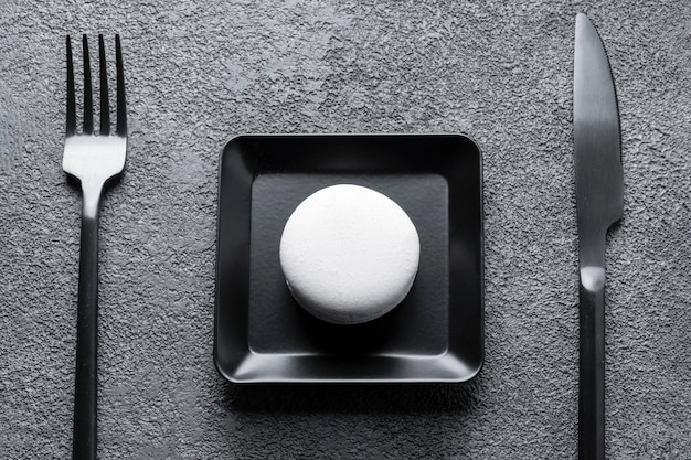 Foto bolo de macarrão branco em um prato quadrado preto. bela composição, minimalismo.