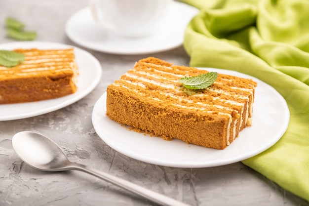 Bolo de mel caseiro com creme de leite e hortelã com uma xícara de café em cinza