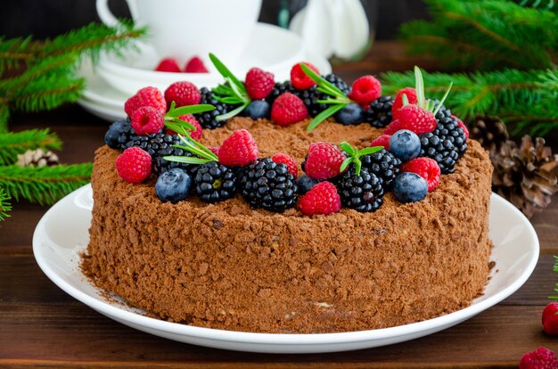 Bolo de mel de chocolate com creme e frutas frescas por cima em um prato branco