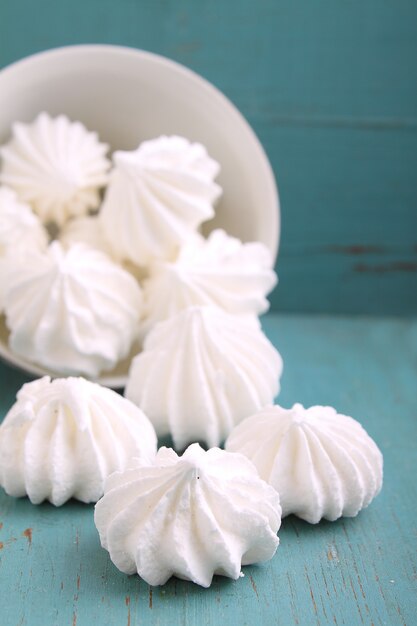 Bolo de merengue branco espalhado sobre um fundo azul de madeira