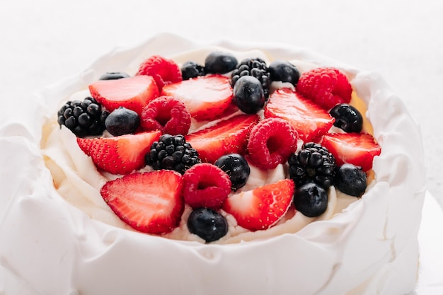 Bolo de merengue Pavlova com frutas frescas no fundo branco