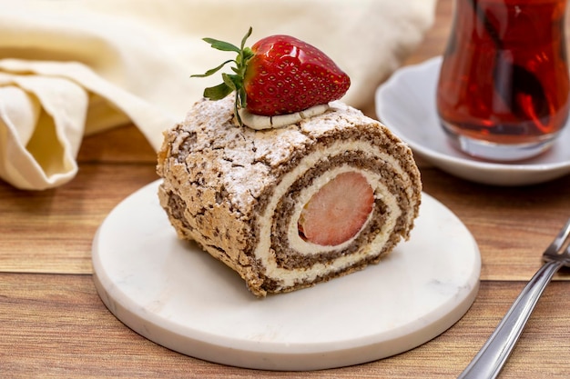 Bolo de morango em um fundo de madeira Bolo com creme de leite e recheio de morango junto com uma xícara de chá