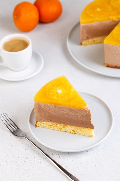 Bolo de mousse de chocolate e laranja com geleia de base de biscoito e círculos de laranja pedaço de cheesecake caseiro e uma xícara de café sobremesa tradicional de férias foco seletivo closeup