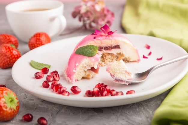 Bolo de mousse rosa com morango e uma xícara de café em uma superfície de concreto cinza. vista lateral, foco seletivo, arrancado.