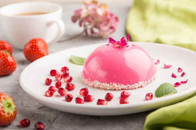 Bolo de mousse rosa com morango e uma xícara de café em uma superfície de concreto cinza. Vista lateral, foco seletivo.