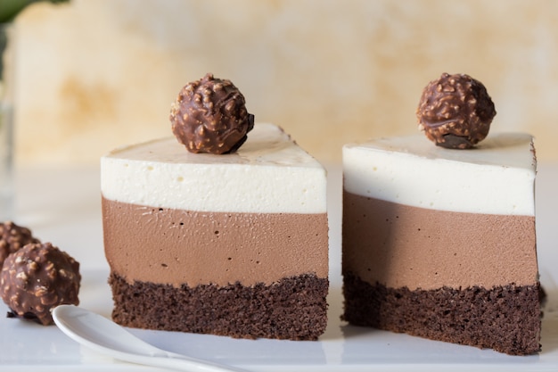 Bolo de mousse "três de chocolate". Pedaço de bolo feito de três camadas de chocolate com suflê de cores diferentes com uma xícara de café