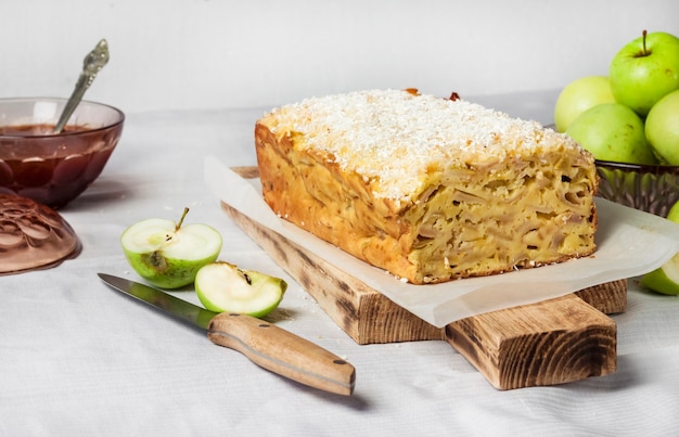 Bolo de nabo de maçã e coco em uma tábua de madeira e maçãs em um vaso