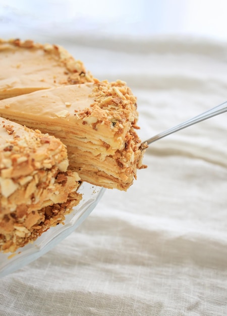 Bolo de napoleão redondo com creme de caramelo e um pedaço cortado em um espaço de cópia de fundo branco