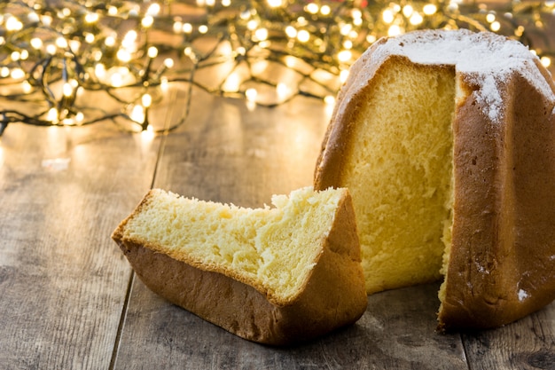 Bolo de Natal Pandoro com açúcar e luz de Natal na mesa de madeira