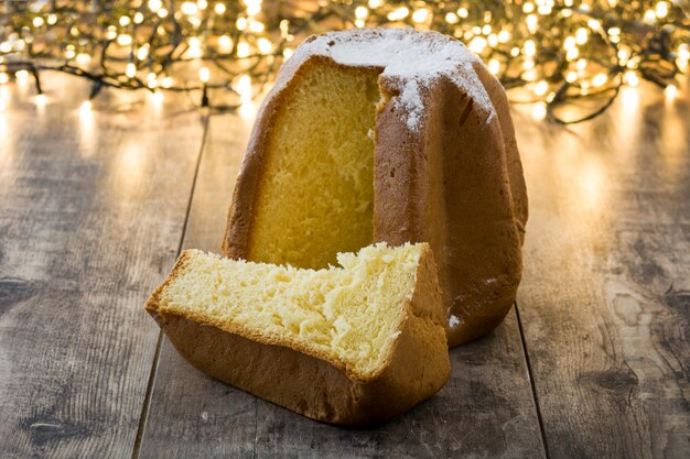 Bolo de Natal Pandoro com açúcar e luz de Natal na mesa de madeira