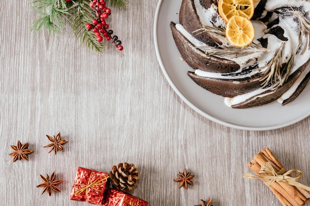 Bolo de Natal tradicional decorado com esmalte, laranja e alecrim na mesa cinza claro, vista superior. Espaço para texto