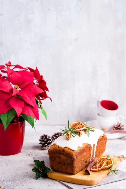 Bolo de pão de frutas polvilhado com glacê, nozes e pedra laranja seca. poinsétia de férias de natal e inverno em