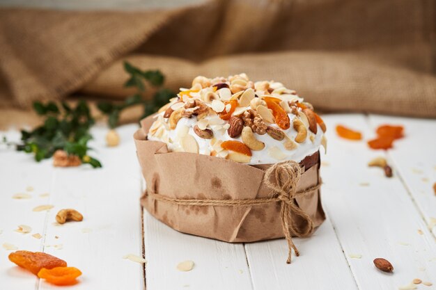 Bolo de Páscoa decorado por nozes e frutos secos em fundo branco de madeira, tradicional Kulich, Paska, pronto para a celebração