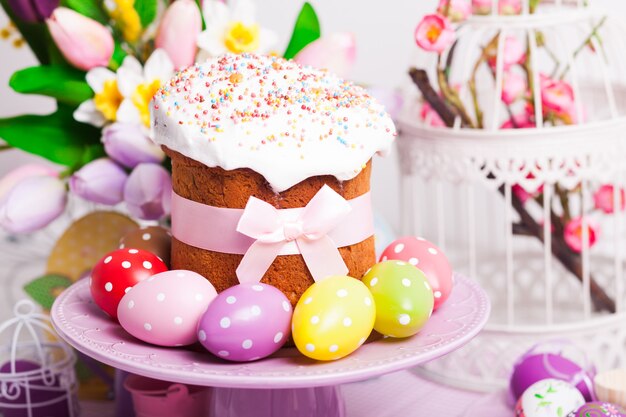 Bolo de Páscoa e ovos de bolinhas coloridas no prato e flores em primeiro plano