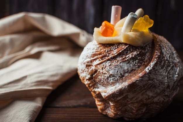 Bolo de páscoa elegante com marshmallows e ursinhos de geléia em um fundo escuro de madeira rústico.