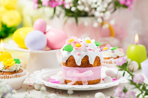 Bolo de Páscoa tradicional com glacê branco decorado flores de açúcar e ovos coloridos.