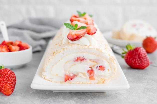 Bolo de Pavlova de rolo de merengue com creme e morangos frescos por cima em um fundo cinza Copiar espaço