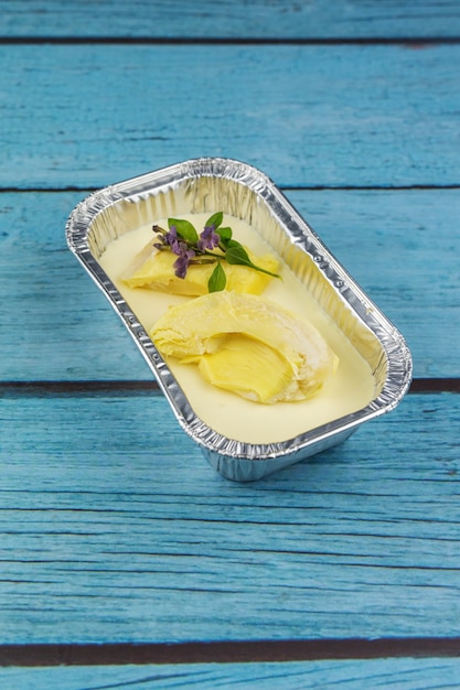 Bolo de queijo caseiro com cobertura de frutas Durian, sobre um fundo azul de madeira