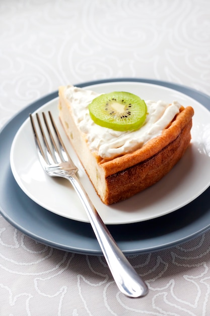 Bolo de queijo caseiro com kiwis e creme em um prato