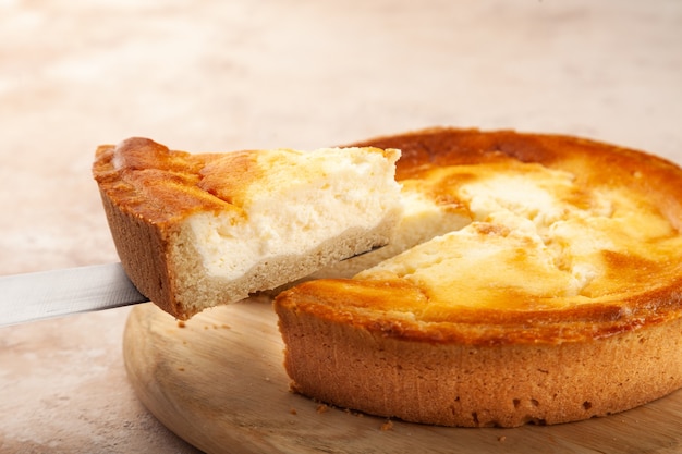 Foto bolo de queijo caseiro, corte um pedaço de torta na faca, prato de madeira, copie o espaço, lugar para texto, vista lateral, close-up