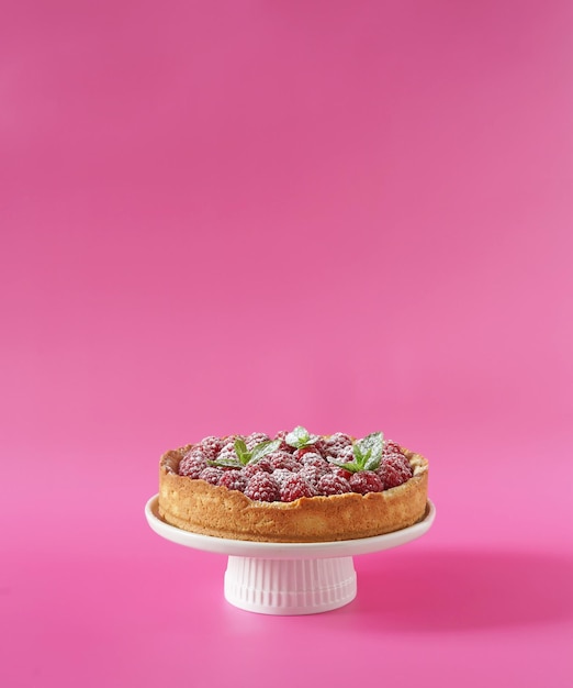 Bolo de queijo com framboesa fresca no carrinho de bolo no espaço de cópia livre de fundo rosa