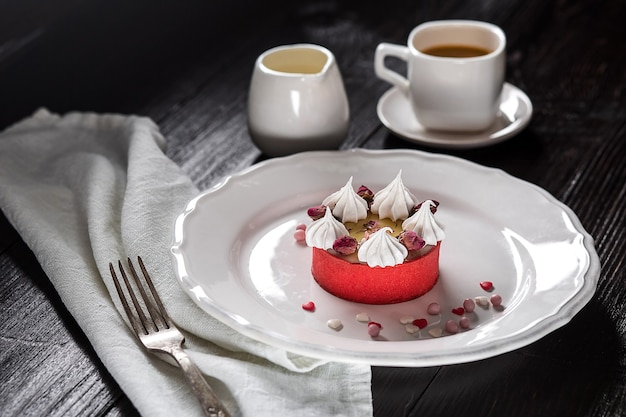 Bolo de queijo de caramelo com creme e flores no fundo de madeira. Uma xícara de café e um bolo em um prato branco