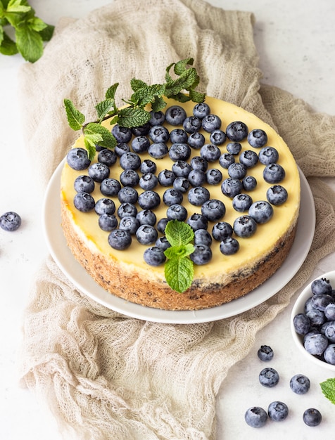 Bolo de queijo de estilo de Nova York, mirtilos e hortelã em um prato branco.