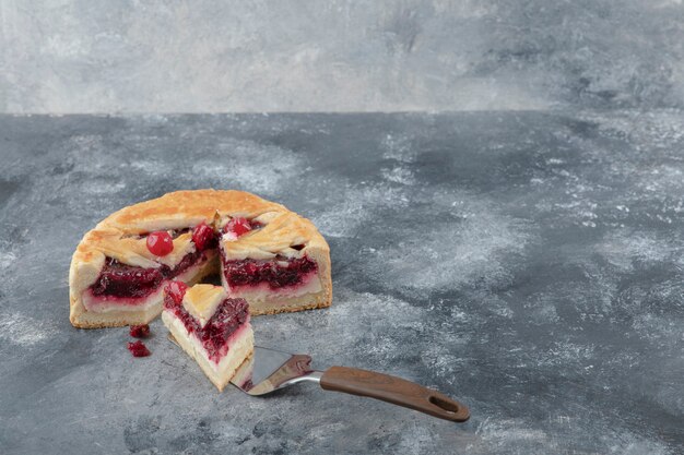 Bolo de queijo saboroso fatiado com frutas colocadas sobre fundo de mármore.