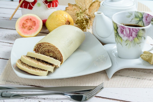 Bolo de Rolo Brötchen Kuchen in Scheiben geschnitten neben Besteck Tasse Kaffee und Guaven.