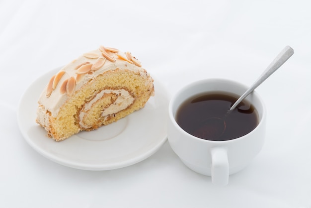 Bolo de rolo de amêndoa no prato branco com bebida quente