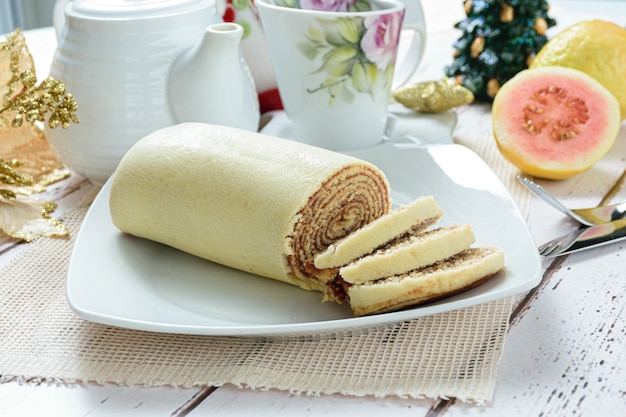 Bolo de rolo de bolo fatiado ao lado de uma decoração de Natal Vista lateral dos doces tradicionais brasileiros.