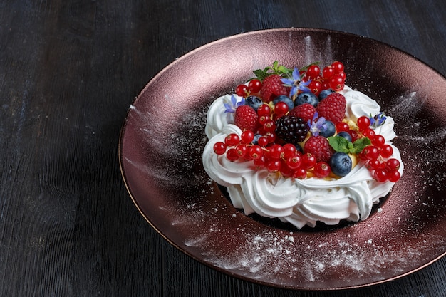 Bolo de sobremesa de merengue com frutas frescas em fundo madeira