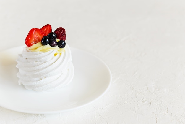 Bolo de sobremesa pavlova com frutas em uma mesa branca. orientação horizontal, copie o espaço.