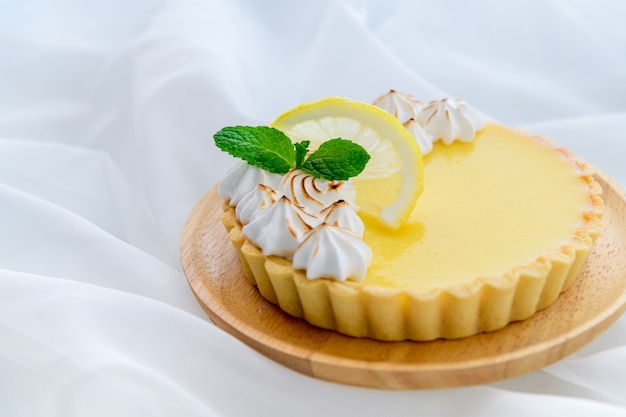 Bolo de torta de limão cítrico em prato de madeira e fundo de pano branco, conceito de bolo e padaria