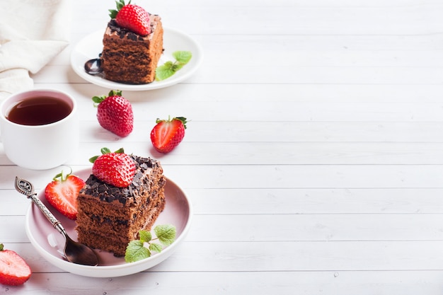 Bolo de trufa com chocolate e morangos e hortelã em uma mesa de madeira branca. foco seletivo. copie o espaço