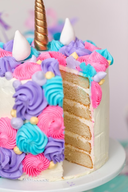 Bolo de unicórnio multicamadas fatiado no carrinho de bolo na festa de aniversário da menina.