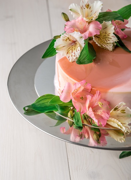 Bolo decorado com flores. bolo de casamento em um carrinho sobre um fundo branco de madeira