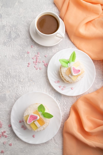 Bolo decorado com leite e creme de coco com uma xícara de café em uma vista superior de fundo de concreto cinza