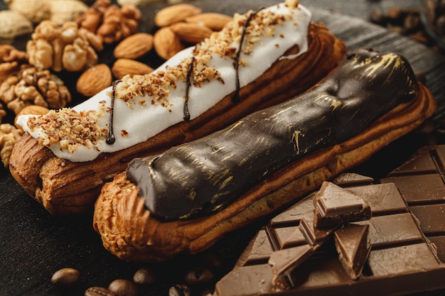 Bolo éclair na placa de madeira escura na mesa preta