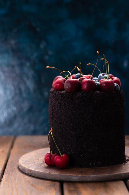 Bolo escuro com frutas por cima um bolo decorado com mirtilos e cerejas