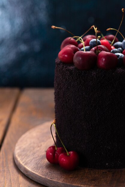 Bolo escuro com frutas por cima Um bolo decorado com mirtilos e cerejas