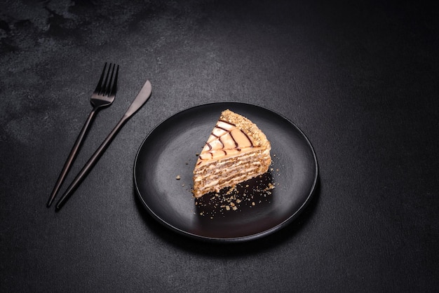 Bolo Esterhazy fatiado em placa preta closeup Delicatessen sobremesa doce com massa de merengue de amêndoa e creme de manteiga