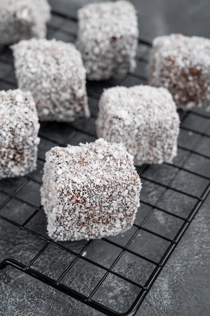 Bolo Lamington australiano em cobertura de chocolate e flocos de coco em um fundo de concreto cinza