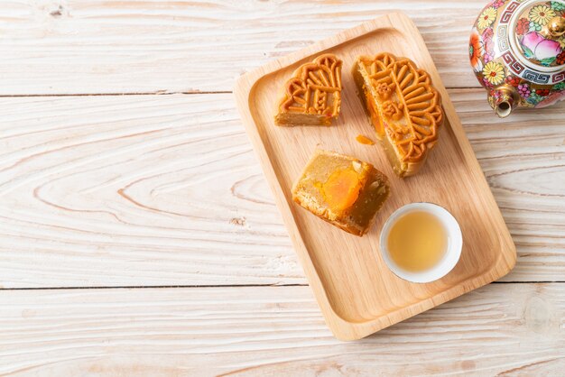 Bolo lunar chinês com sabor de durian e gema de ovo com chá no prato de madeira